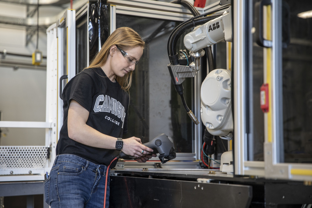 A woman wearing a black լ t-shirt works on something in a technical environment.